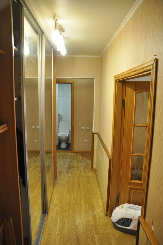 Светлый коридор с зеркальными шкафами и деревянными дверями, ведущий в ванную комнату. Уютная атмосфера, паркетный пол.