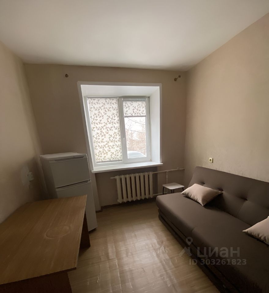 Светлая комната 17 кв.м на 2 этаже, Екатеринбург. Минималистичный интерьер, диван, стол, холодильник, окно с жалюзи.