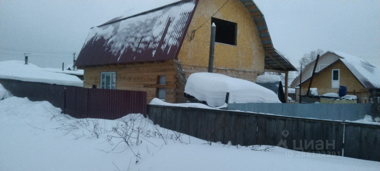 Деревянный дом в загородном стиле с двускатной крышей, покрытой красной металлочерепицей. Стены отделаны желтым утеплителем, что придает зданию современный вид. Окна расположены на фасаде, одно из них не имеет стекла, что свидетельствует о незавершенности работ. Вокруг дома видна снеговая завеса, создающая атмосферу уединения. Забор из металлических панелей окрашен в темно-бордовый цвет, что контрастирует с белизной снега. Общая эстетика пространства создает ощущение спокойствия и уединенности, характерного для загородной жизни.