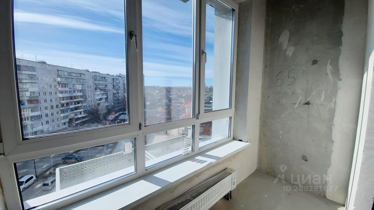 Уютный уголок с большими окнами, обеспечивающими естественное освещение. Стены имеют незавершенную отделку, с видимыми бетонными поверхностями. Просторная подоконная зона приглашает к отдыху, а радиатор под окном добавляет комфорт в холодное время года. Пол выполнен из гладкого материала, готового к укладке покрытия. Общая атмосфера помещения создаёт ощущение открытости и возможности для дальнейшей индивидуализации интерьера.