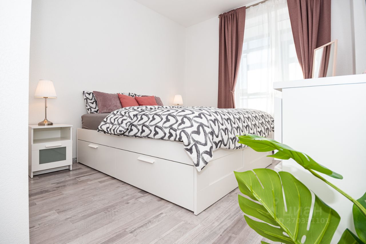 Светлая и уютная спальня с современной мебелью и декором, большая кровать, окна с плотными шторами, стильный интерьер