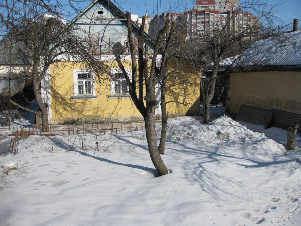 Участок в Липецке. Зимний вид на дом с желтым фасадом, деревья и снег. Удобное расположение в тихом районе.