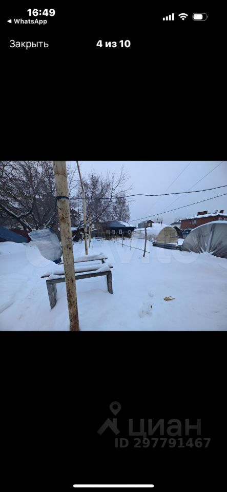 На фотографии виден участок, покрытый снегом, с деревянной скамейкой и столом. Вокруг расположены палатки и деревья, создающие атмосферу уюта. Скамейка выполнена из дерева и имеет простую конструкцию. На переднем плане видны следы на снегу, которые добавляют динамики в композицию. Цвета в основном холодные, преобладает белый от снега и серый от палаток. Общая обстановка передает ощущение спокойствия и уединения, что характерно для загородного отдыха в зимний период.