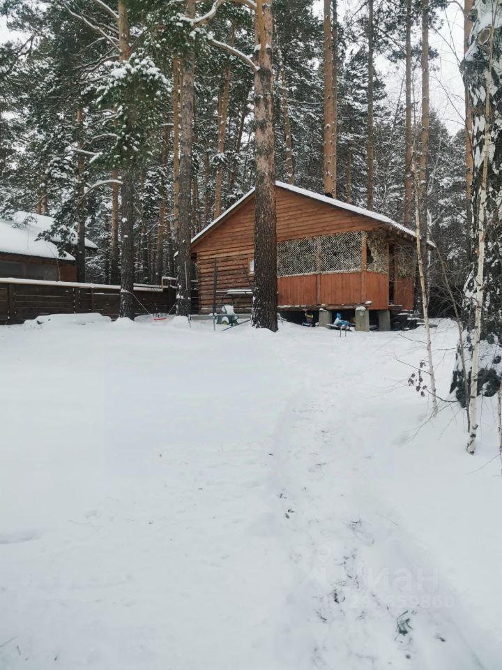 Деревянный дом в загородном стиле с наклонной крышей и террасой, обшитый натуральным деревом. Архитектурные элементы включают декоративные решетки и широкие подоконники. Структурные особенности: небольшая терраса, выходящая на природу, и окна, обеспечивающие хорошее освещение. Внешние стены выполнены из бруса, что придаёт уютный вид. Цветовая гамма - теплые деревянные оттенки, гармонирующие с окружающей природой. Финишные детали включают деревянные перила и элементы отделки, создающие комфортную атмосферу. Пространство идеально подходит для отдыха на природе.