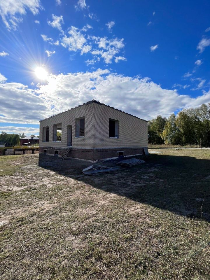 Дом в современном архитектурном стиле с кирпичной отделкой. Стены выполнены из светлого кирпича, что придает зданию современный вид. На фасаде видны большие оконные проемы, которые обеспечивают хорошее освещение. Крыша двускатная, покрыта темной черепицей. Фундамент выполнен из бетона, что обеспечивает прочность конструкции. Внешний вид здания аккуратный, без заметных дефектов. Основные цветовые оттенки — светло-бежевый и темно-серый. Пространство вокруг дома еще не благоустроено, но предполагает возможность для ландшафтного дизайна.