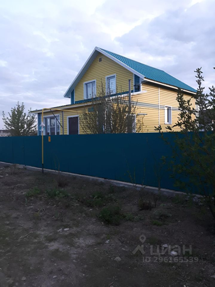 Продается дом в Барнауле, общая площадь 100 кв.м. Желтый фасад, зеленая крыша, высокий забор. Без отделки, готов к ремонту.