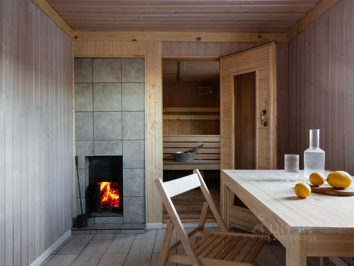 Уютная комната с камином и сауной в доме, Екатеринбург. Просторное помещение с деревянной отделкой, столом и стульями.