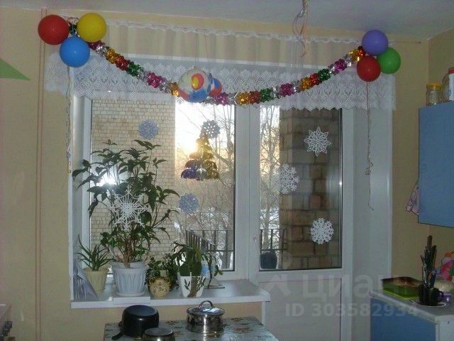 Уютная кухня с видом на двор, украшенная гирляндой и растениями. Светлое помещение, окна на третьем этаже, Екатеринбург.