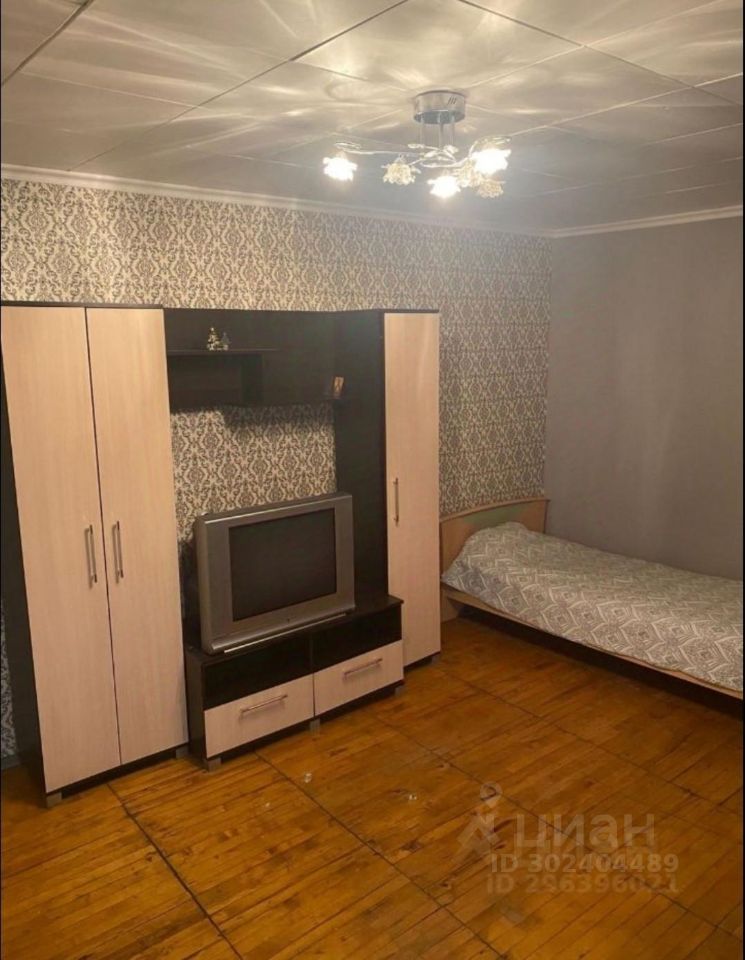 Светлая комната с мебелью, обои с узором, деревянный пол, телевизор, шкаф, кровать. Уютное жилье в Екатеринбурге, 8 этаж.