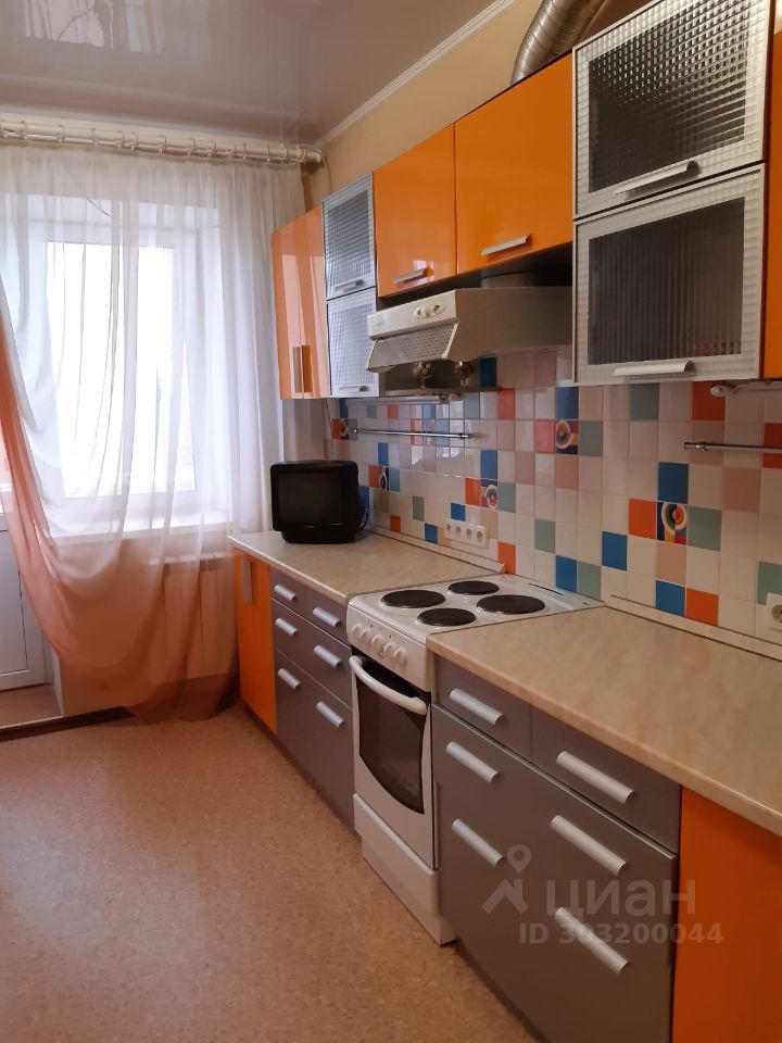 Светлая кухня с яркими оранжевыми шкафами и плиткой, просторная и уютная, с выходом на балкон. Идеально для комфортного проживания.