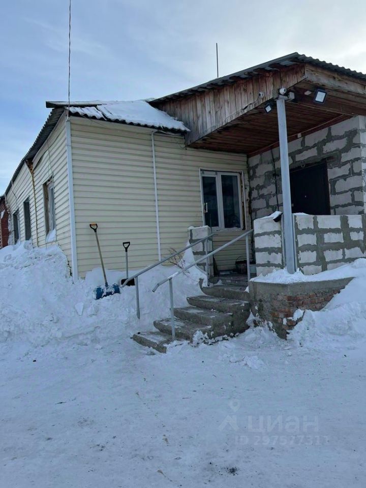 Здание выполнено в простом архитектурном стиле с элементами современного дизайна. Видны структурные особенности, такие как каменные и деревянные элементы, а также крыша с металлической отделкой. Входная зона оформлена лестницей с перилами, что обеспечивает удобный доступ. Основные характеристики пространства включают большие окна, обеспечивающие естественное освещение, и отделку из светлого сайдинга. Материалы, используемые в конструкции, включают бетон, дерево и металл, а цветовая палитра состоит из нейтральных оттенков, создающих гармоничное впечатление.