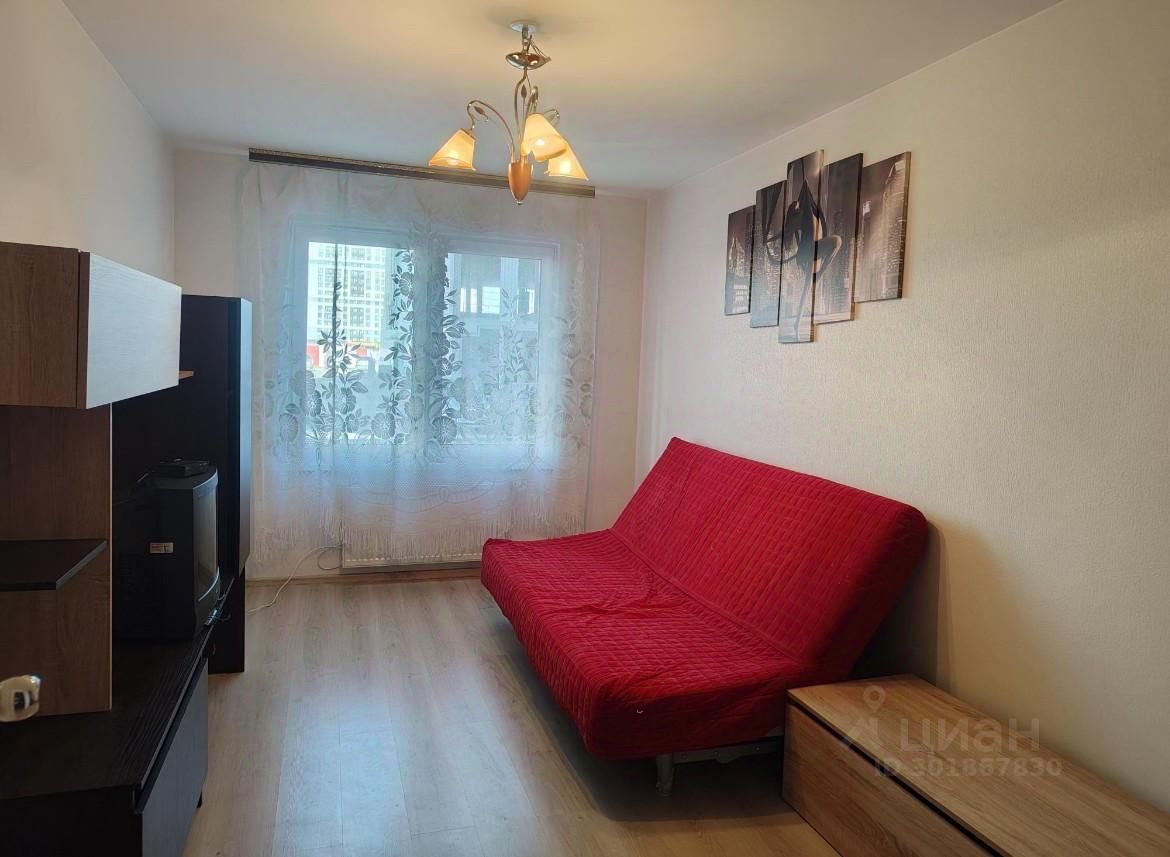 Светлая 1-комн. квартира в Екатеринбурге, 36 кв.м, кухня 14 кв.м, 1 этаж. Современный интерьер, уютная гостиная с красным диваном.