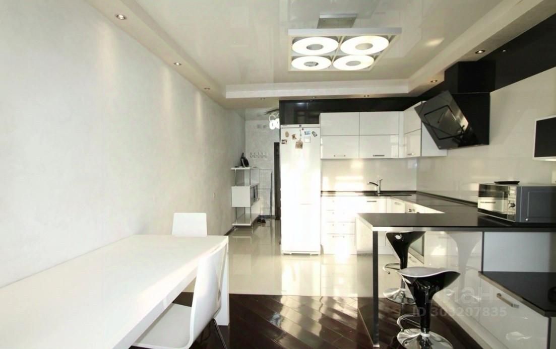 Светлая однокомнатная квартира на 19 этаже в Екатеринбурге. Современная кухня с белой мебелью и стильным освещением.