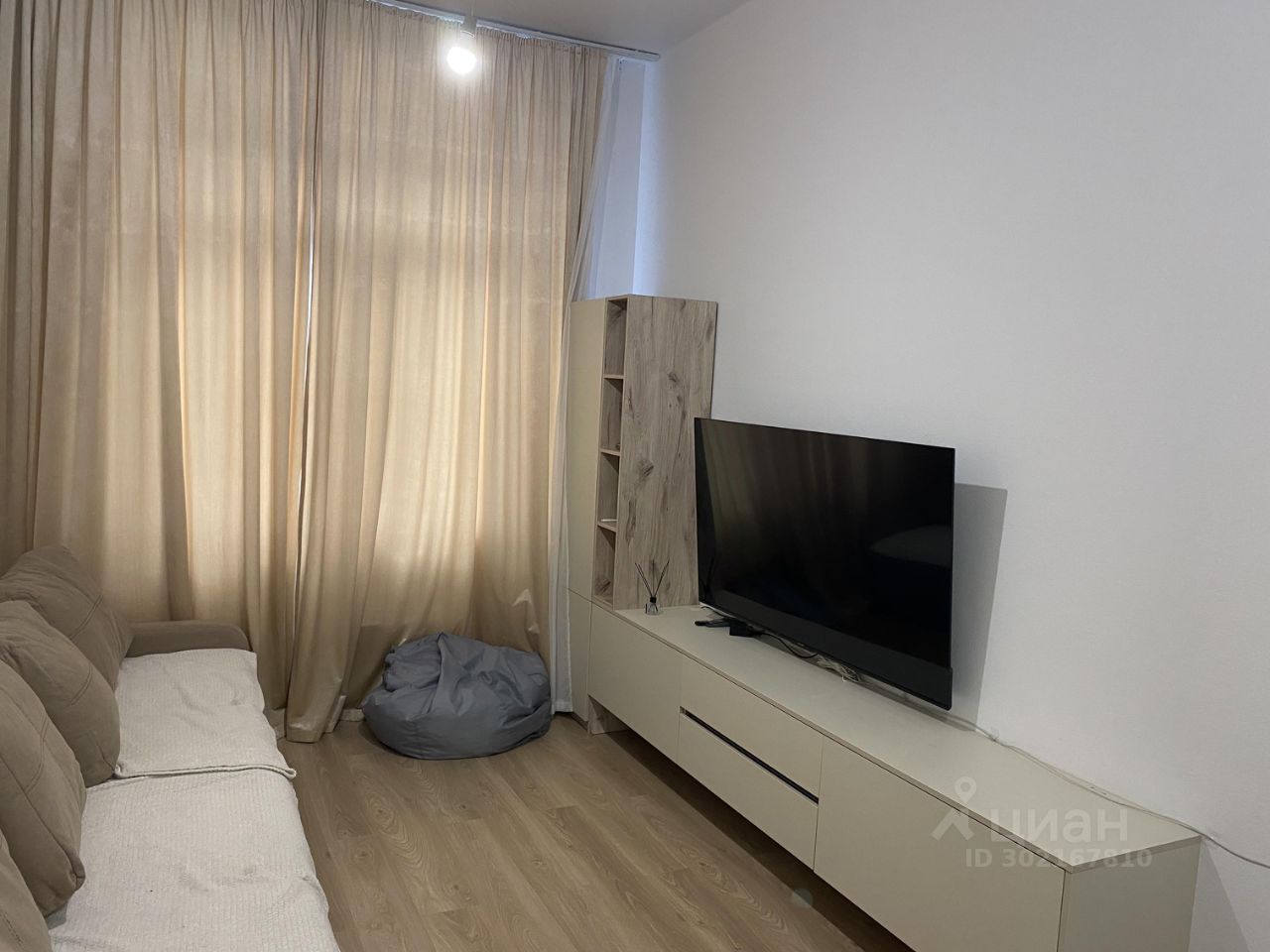 Светлая гостиная с уютным диваном, современным телевизором и стильной мебелью. Просторная квартира в Екатеринбурге, 63 кв.м, 3 комнаты.