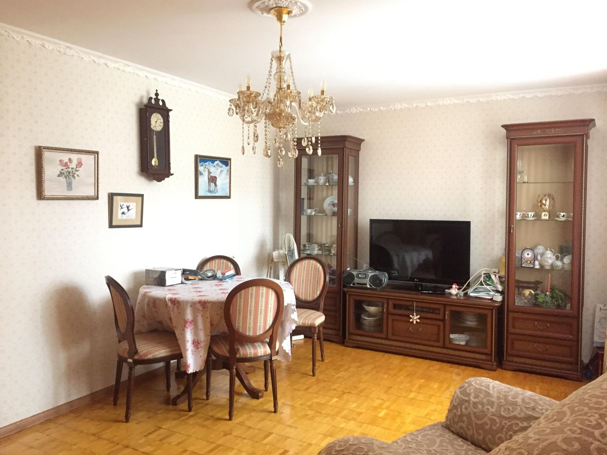 Уютная гостиная с обеденной зоной, классическая мебель, паркетный пол, люстра, часы на стене, витрина с посудой, телевизор