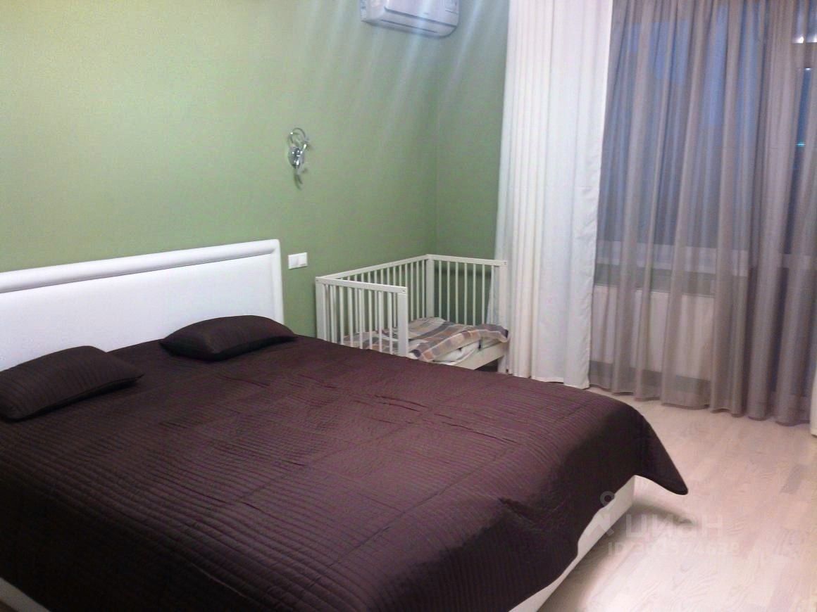 Светлая спальня с большой кроватью и детской кроваткой. Зеленые стены, кондиционер, большие окна с шторами. Уютная и просторная комната.