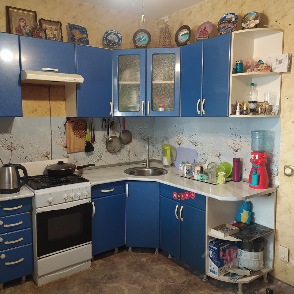 Уютная кухня с яркими синими шкафами, газовая плита, просторная рабочая зона, декоративные тарелки на стенах.