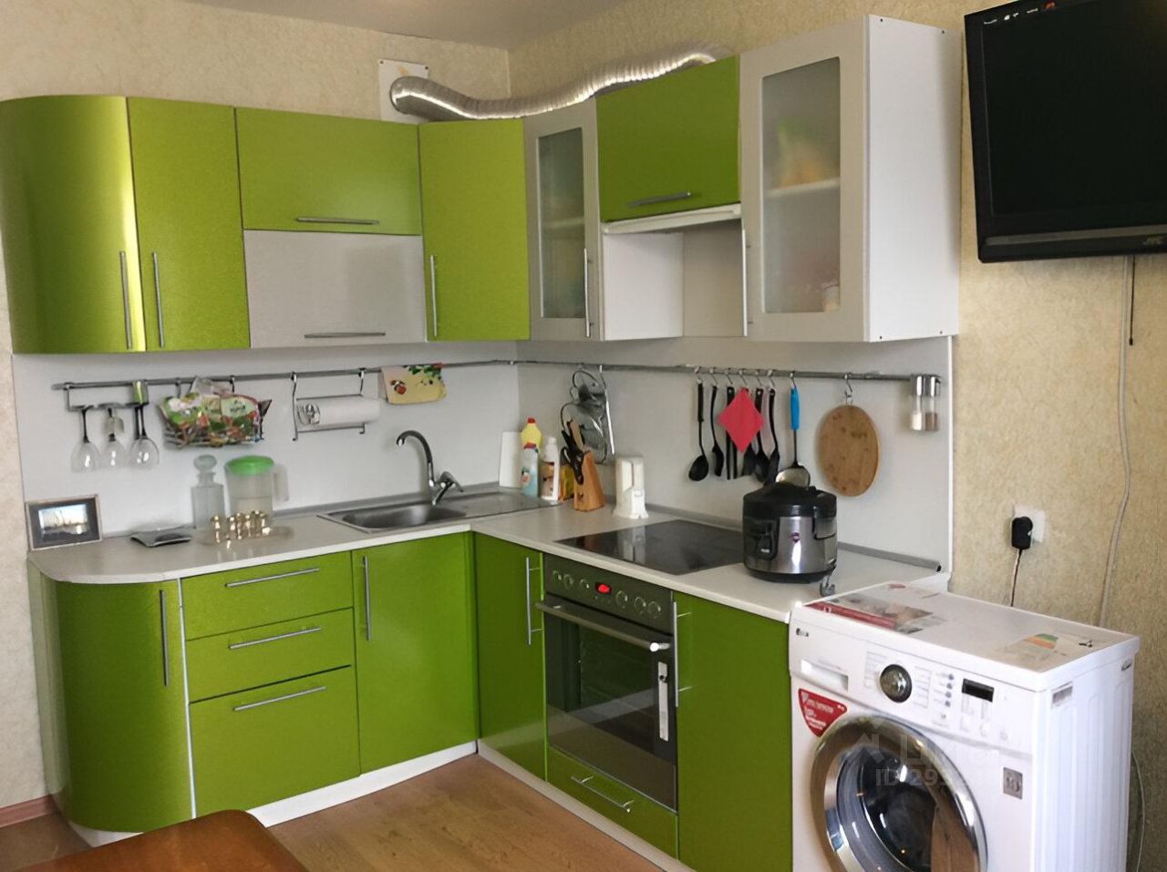 Кухня выполнена в современном стиле с яркими зелеными фасадами и белыми элементами. Структурные особенности включают угловую планировку и встроенные шкафы, что создает функциональное пространство. Основные характеристики включают мойку, плиту, духовку и стиральную машину, расположенные в удобной близости. Использованы гладкие поверхности и металлические ручки, что придает интерьеру современный вид. Цветовая гамма состоит из ярко-зеленого и белого, что создает освежающую атмосферу. В отделке присутствуют элементы из нержавеющей стали, добавляющие эстетическую привлекательность.
