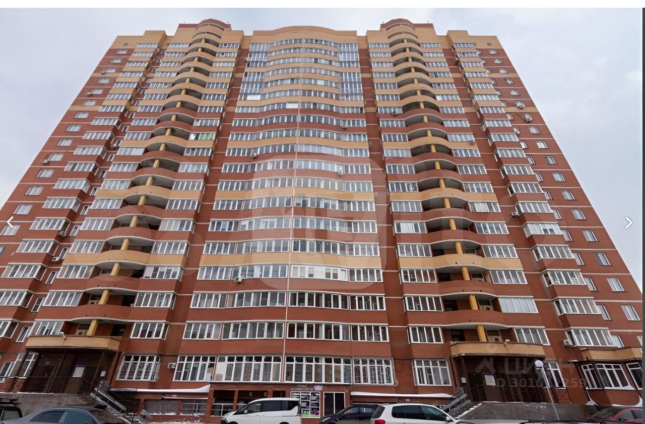 Здание выполнено в современном архитектурном стиле с элементами многоэтажной застройки. Фасад украшен большими окнами, которые создают светлую атмосферу. Балконы с округлыми формами добавляют динамики в общий вид. Структура здания включает несколько этажей, а нижняя часть оформлена в более светлых тонах. Основные материалы – кирпич и стекло, что придаёт зданию современный и стильный вид. Цветовая палитра включает коричневые и светлые оттенки, гармонично сочетающиеся друг с другом. Общий дизайн фокусируется на функциональности и эстетике, создавая привлекательное жилое пространство.