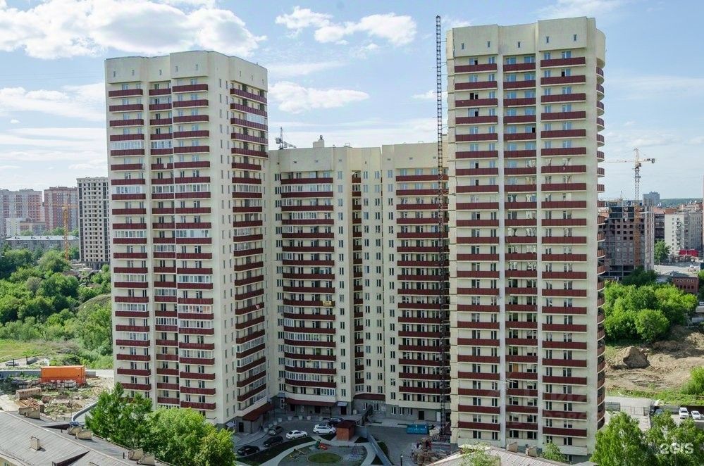 Многоэтажное здание выполнено в современном архитектурном стиле с элементами минимализма. Фасад украшен чередующимися светлыми и темными панелями, создающими динамичный визуальный эффект. Структурные особенности включают балконы с металлическими перилами, а также большие окна, обеспечивающие естественное освещение. На нижнем уровне расположены входные группы и парковка. Использованы качественные строительные материалы, такие как бетон и стекло, в нейтральных цветах, что подчеркивает современный облик здания. Общая композиция создает ощущение простора и уюта.