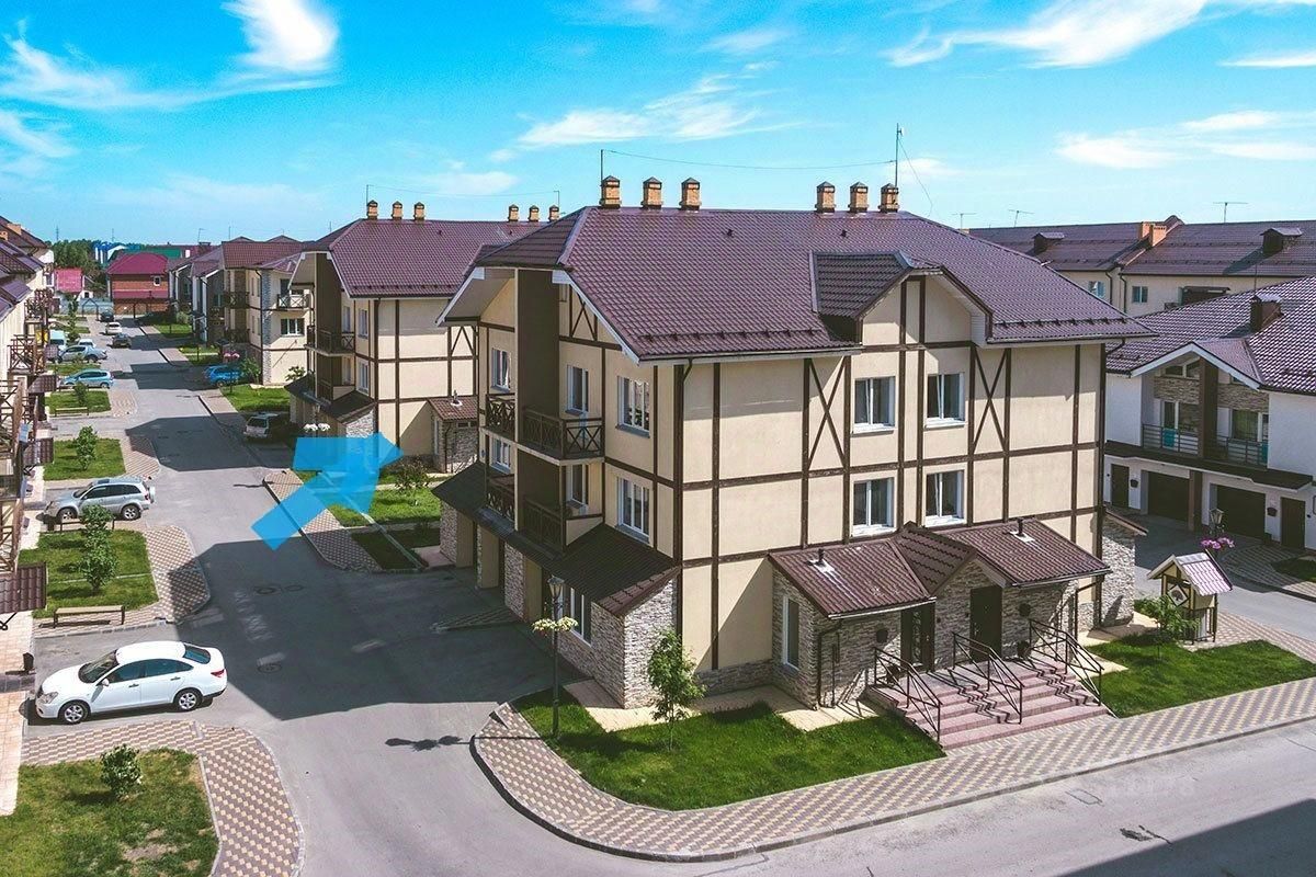 Архитектурный стиль здания характеризуется сочетанием современного и традиционного дизайна, с использованием светлых фасадов и темных деревянных элементов. Видны структурные особенности, такие как симметричное расположение окон и балконов, а также крыша с черепицей. Входная зона оформлена ступенями и перилами, что придает ей элегантность. Основные материалы включают кирпич и дерево, а цветовая гамма состоит из светлых и темных тонов, создающих контраст. Общее оформление пространства подчеркивает уют и комфорт, характерные для загородного жилья.