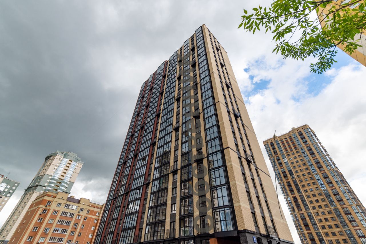 Современное жилое здание с элементами минимализма, выполненное в сочетании кирпичных и стеклянных фасадов. Высокие окна обеспечивают обилие света и открывают вид на окружающую местность. Структурные особенности включают четкие линии и геометрические формы, создающие гармоничный облик. Цветовая палитра включает теплые оттенки кирпича и холодные тона стекла. Фасад украшен балконами, что добавляет динамики. Визуально здание выглядит современно и стильно, привлекая внимание своей архитектурной выразительностью и функциональностью.