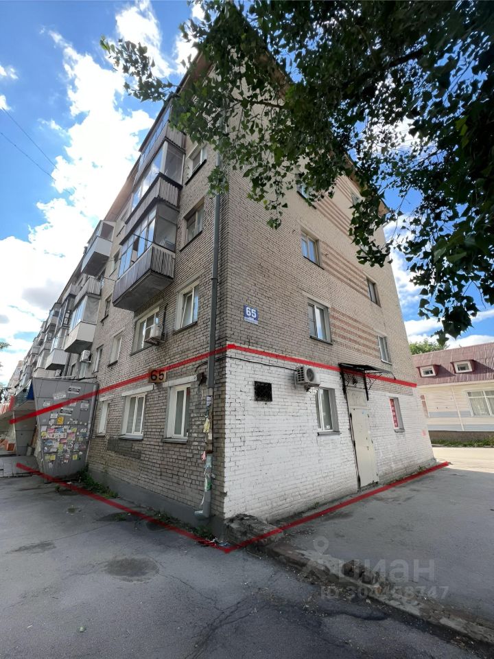 Здание выполнено в простом кирпичном архитектурном стиле с элементами функционализма. Видны два этажа, на которых расположены окна с простыми рамами и балконы с застеклением. Основные структурные особенности включают ровные линии и симметричное размещение окон. Фасад окрашен в светлые тона, что придаёт зданию современный вид. Материалы включают кирпич и металл, а отделка минималистична, без лишних украшений. Цветовая гамма нейтральная, с акцентами на белый и серый. Входная дверь и кондиционер добавляют функциональные элементы к общему дизайну.