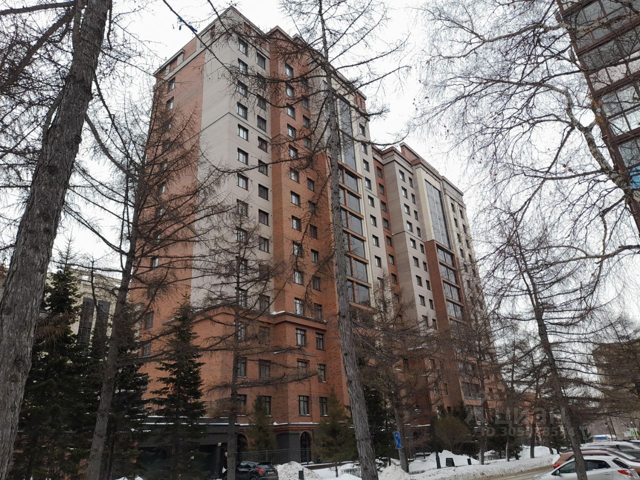 Здание выполнено в современном архитектурном стиле с элементами минимализма. Фасад сочетает кирпичную и панельную отделку, что придаёт ему солидный вид. Структурные особенности включают большие окна, обеспечивающие естественное освещение, и балконы, которые добавляют функциональности. Видно несколько этажей, с симметричной композицией окон. Цветовая гамма в основном состоит из теплых оттенков красного и бежевого, что создает уютную атмосферу. Отделка аккуратная, с акцентом на современный дизайн и комфорт, что делает здание привлекательным для проживания.