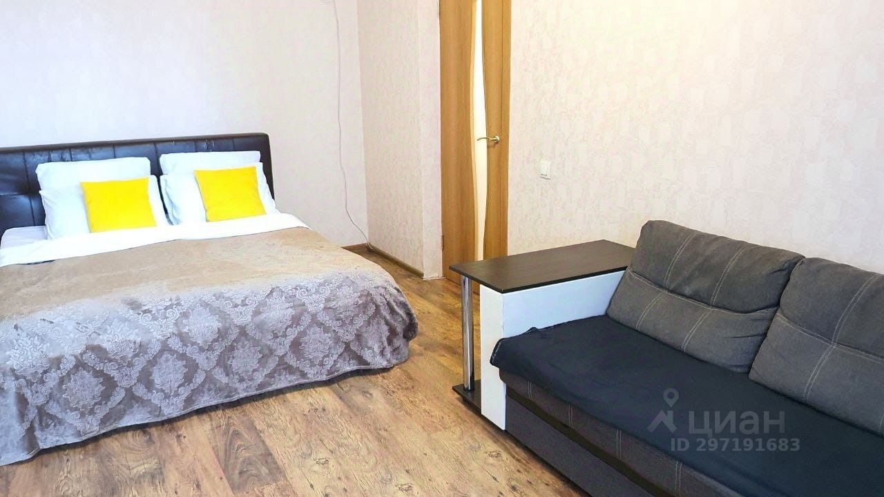 Уютная комната с двуспальной кроватью и диваном, светлые стены, деревянный пол. Идеально для краткосрочной аренды в Екатеринбурге.