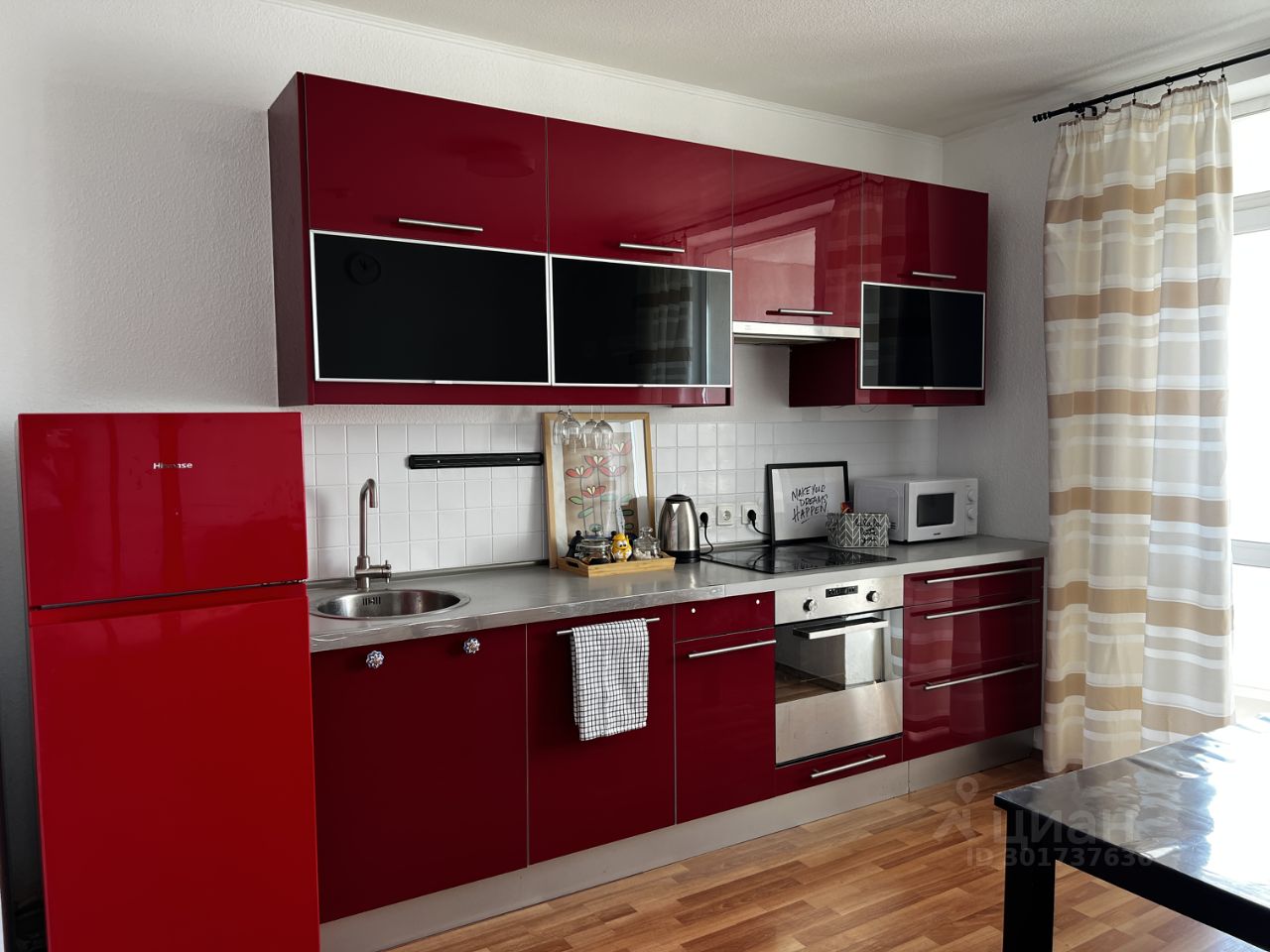 Современная кухня с яркими красными фасадами, встроенной техникой и обеденной зоной. Светлое помещение, уютная атмосфера.