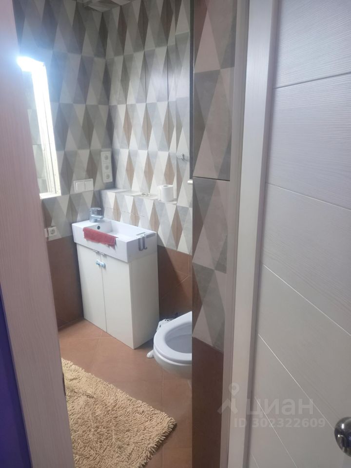 Светлая ванная комната с современной плиткой, умывальником и зеркалом. Уютный интерьер, теплые тона, чистота и комфорт.