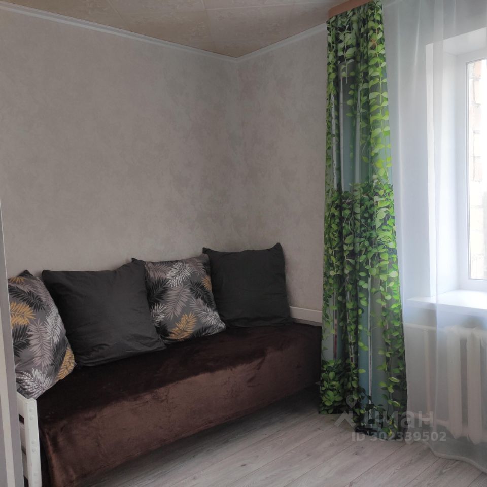 Уютная комната с мягким диваном и яркими шторами, расположенная на 7 этаже в Екатеринбурге. Идеально подходит для краткосрочной аренды.