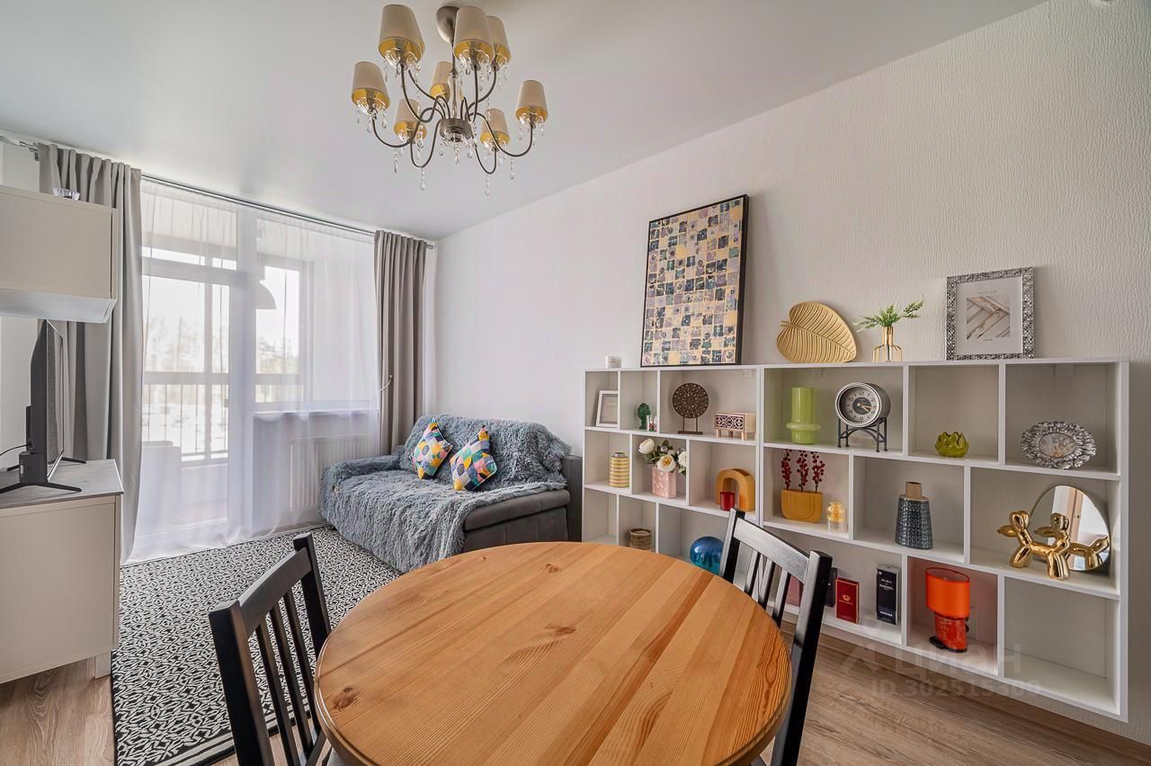 Светлая квартира в Екатеринбурге, 39 кв.м, кухня 20 кв.м, 3 этаж. Современный интерьер, уютная гостиная с диваном и полками, обеденный стол.