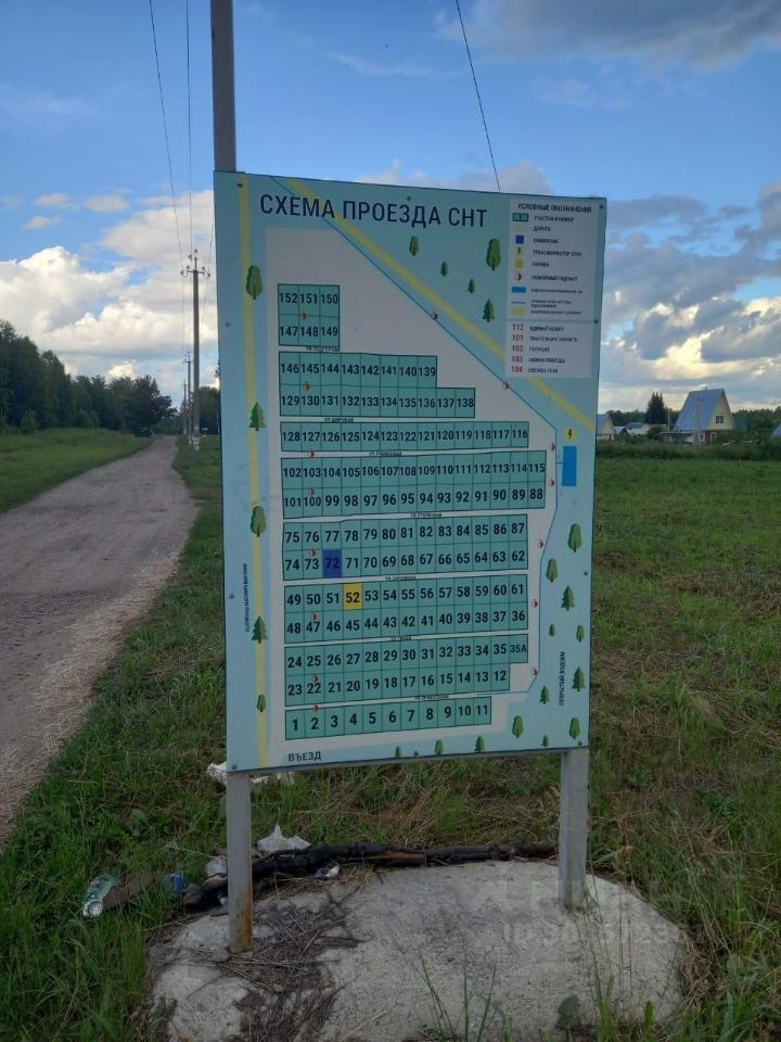 На фотографии изображена схема проезда СНТ. На табличке представлены номера участков, расположенных в виде сетки, с обозначением проездов. Схема оформлена в светлых тонах с зелеными элементами, символизирующими деревья. В верхней части указаны условные обозначения для различных объектов, таких как дороги и дома. Нумерация участков идет по порядку, что облегчает ориентирование. Фон таблички нейтральный, с небольшими элементами дизайна, подчеркивающими функциональность схемы.