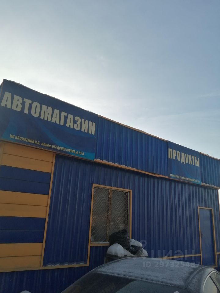 Здание выполнено в современном архитектурном стиле с использованием ярких цветовых решений. Фасад окрашен в синий и желтый цвета, что придает ему заметный вид. На стенах размещены вывески с названиями магазинов, что указывает на коммерческое назначение. Структурные элементы включают окна с решетками и дверь, выполненные из металла. Видно, что здание имеет простую, но функциональную планировку. Основные материалы - металл и краска, что обеспечивает долговечность и легкость в обслуживании. Общая атмосфера пространства выглядит доступной и практичной.